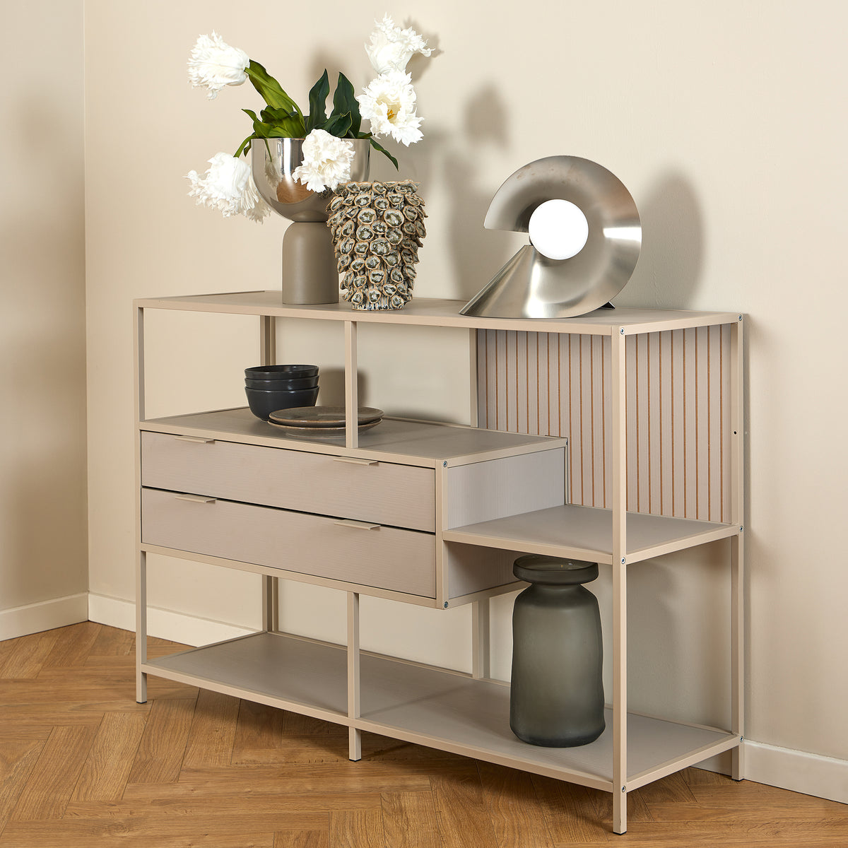 Étagère basse Skeleto 114 x 78, mélaminé gris, avec des fleurs blanches dans un vase et une lampe argentée posée sur le plateau