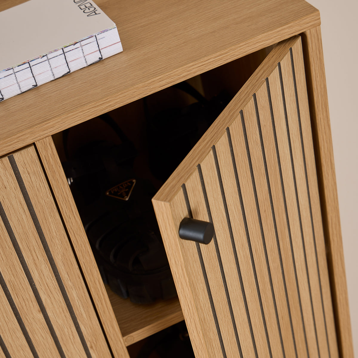 Armoire à chaussures Bambouz 99 x 141 – détail des portes entrouvertes avec une poignée noire et des chaussures sur l'étagère