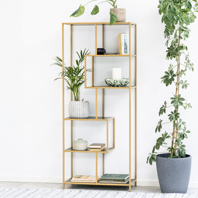 Étagère Skeleto 77 x 185 en mélamine noire (cadre doré) contre un mur blanc, entourée de plantes en pots – une étagère glamour