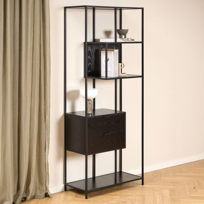 Étagère Skeleto 77 x 185, mélaminé noir, devant un mur clair et un rideau en lin, avec une lampe et des livres