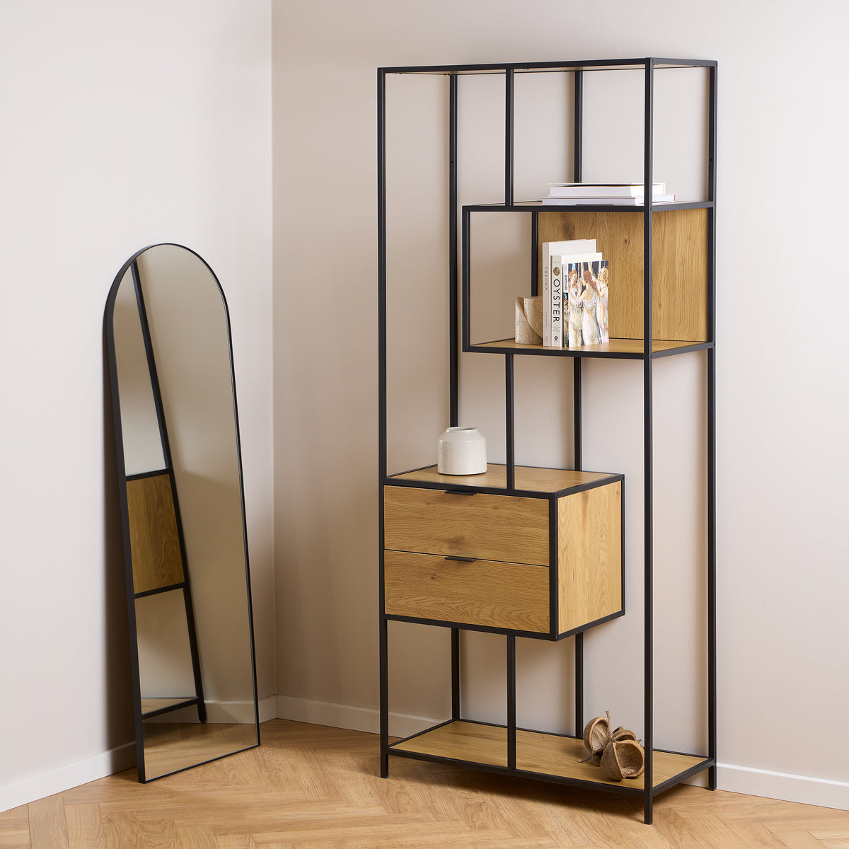 Étagère Skeleto 77 x 185 en chêne sauvage dans un intérieur lumineux, à côté d'un miroir en forme d'arc, avec des livres et un vase sur les étagères