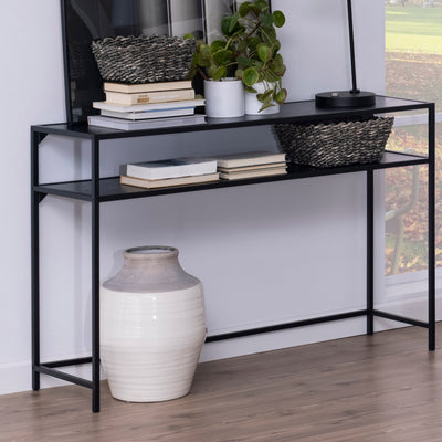 Console Skeleto 120 x 79, en mélaminé noir, placée contre le mur, avec des paniers, des livres et une plante, et un vase en dessous