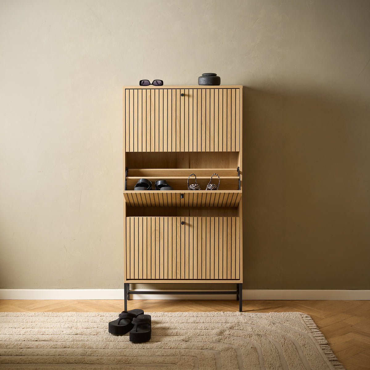 Meuble à chaussures Bambouz 72 x 141 dans l'entrée, au sol en chevrons – compartiment central à porte battante contenant les chaussures, tapis et décorations