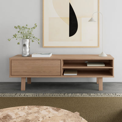 Meuble TV Lurisse 160 x 50, chêne blanchi sous l'illustration, avec une lampe et un vase, devant une table basse en marbre dans le salon